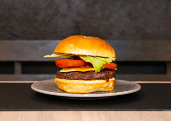 Hamburger with bread, salad, meat, cheese and sausage on top of a table. Delicious fast food burger. Burger ready to eat.