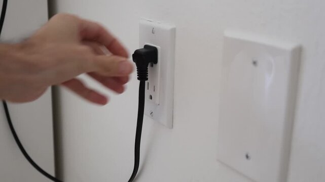 hand put electric plug to outlet