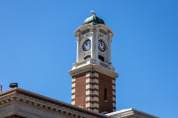 Low angle view of an exterior cupola and clock tower on a exterior brick building in bright sunlight with blue sky