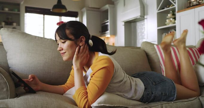 Rose bouquet drawing focus, Asian woman lying on sofa at home scrolling smartphone messages for fun