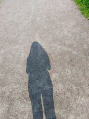 Shadow of the woman on a concrete path in the park with copy space