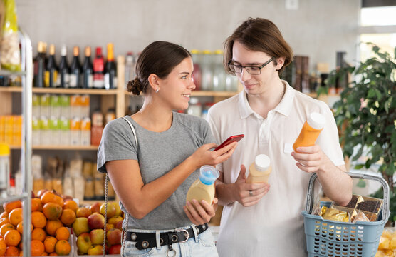 Couple young man and young woman scanning qr code for sauces at grocery store