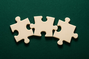 Fototapeta premium Three Interlocking Puzzle Pieces on Green Background