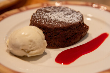 Chocolate lava cake with a scoop of vanilla ice cream and raspberry sauce 