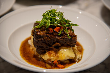 Short rib on mashed potatoes topped with greens