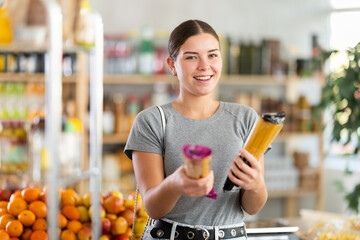 Youth girl choose and buy spaghetti in store. Market visitor consider and make choice of...