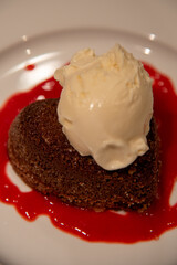 Heart shapped chocolate lava cake with a scoop of vanilla ice cream and raspberry sauce