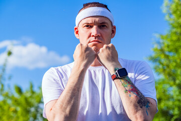 A determined individual practicing an intense workout outdoors with a focused expression and a headband in a green park during daytime