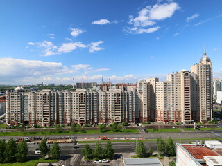 The urban skyline features striking buildings against a blue sky, with lush green spaces