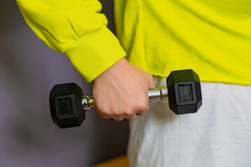 Woman in Yellow Hoodie Lifting dumbbell Against a Purple Wall