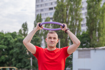 Obraz premium A man exercises outdoors using a fitness ring in a park during late afternoon near playgrounds and sports areas