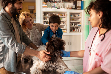 Family with their pet dog at a veterinary clinic talking with a veterinarian