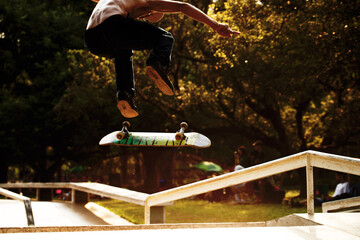 Skatista fazendo manobras com seu skate em pista em parque público.  