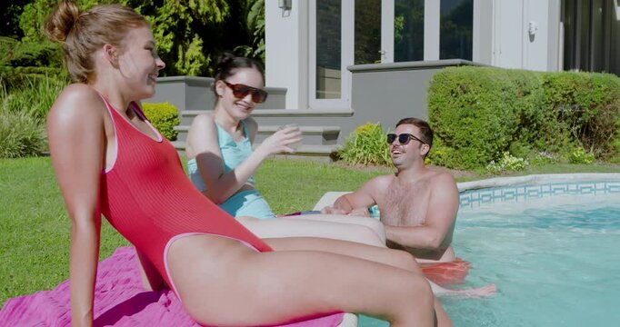 Diverse friends clinking cups poolside welcoming African American woman drifting on donut float
