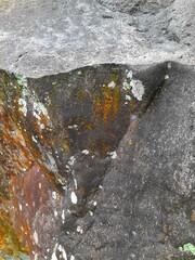 Close-up of a natural rock surface with a rough, uneven texture, visible cracks, and earthy tones,...