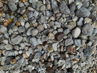 A varied pile of grey and brown river rocks, showcasing natural textures and shapes, ideal for...