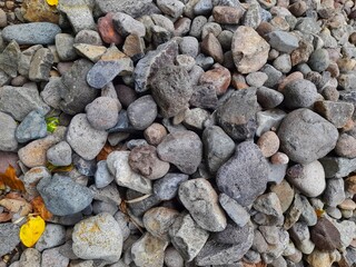 A varied pile of grey and brown river rocks, showcasing natural textures and shapes, ideal for...