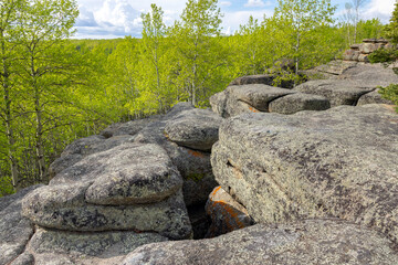 Huge rocks structures geological site in the place of ancient prehistoric ocean trench, nestled within a green forested environment. Rim rocks formation, Western Canada Sedimentary Basin, Alberta