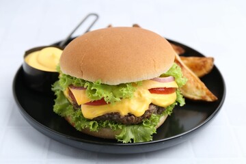 Tasty cheeseburger with sauce and potato wedges on white table, closeup