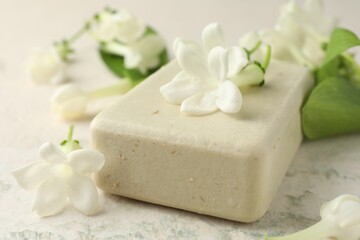 Bar of soap and jasmine flowers on light table, closeup