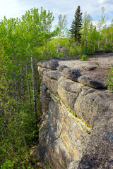 Huge rocks structures geological site in the place of ancient prehistoric ocean trench, nestled within a green forested environment. Rim rocks formation, Western Canada Sedimentary Basin, Alberta