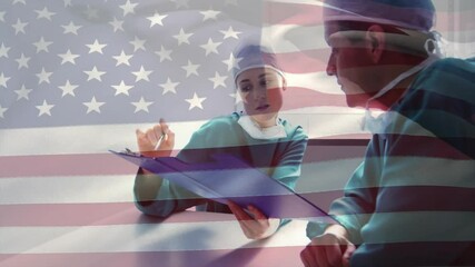 Female surgeon opening patient chart for review and annotating while male surgeon nodding in clinic