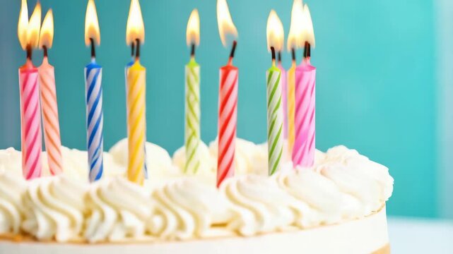 Festive birthday cake adorned with multiple burning candles against a light turquoise background for a celebration event.