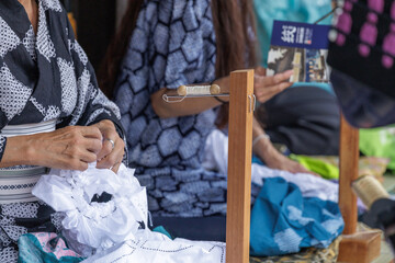 Artisan engages in tying cone shaped knots into fabric used in traditional Japanese...