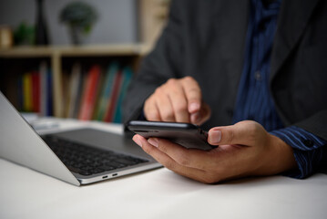 Hand holding smartphone online working on a laptop, modern digital social media network and business marketing finance technology.
