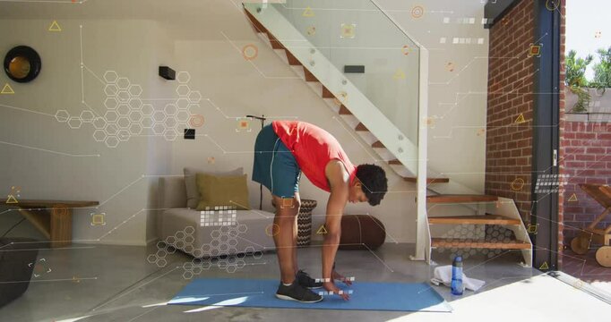 Man standing on blue mat in living room, starting forward bend for home fitness hamstring stretch