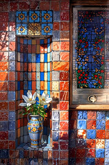 impressionist painting of vase of flowers in small exterior multicolored tile wall