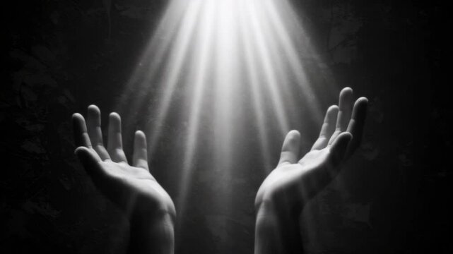 A person's hands reaching up into bright light from above. Spiritual concept of hope, guidance, or divine intervention. Black and white footage.
