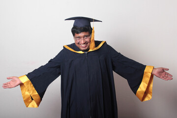30-year-old dark-skinned Latino man with glasses wears a cap and gown to celebrate his graduation...