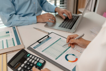 the company's statistics department staff is checking the figures form the graph in the document for recording, accounting, finance, marketing, entrepreneur, paperwork, office