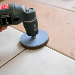 Obraz premium Grinding the bevel of ceramic tiles using a grinding stone with a drill.