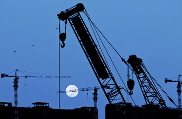 Full moon on the silhouette of a construction site crane