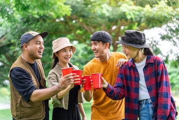 Happy asian diverse group friends enjoy drinking a beer together. They feeling relaxed and refreshing while camping in the nature. Recreation and journey outdoor activity lifestyle.