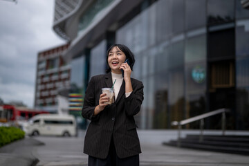 Fototapeta premium A woman is talking on her cell phone while holding a cup of coffee