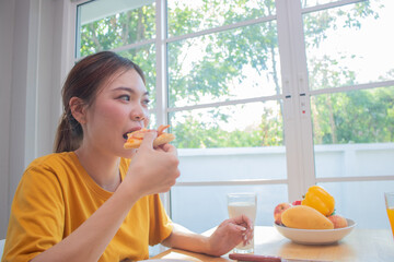 Fototapeta premium Two elegant young women sit in a house, smiling and clinking glasses of juice and breakfast of positive friendship, bonding and unity.
