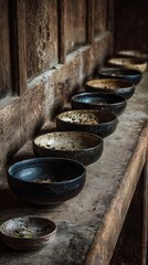 Row of handcrafted ceramic bowls on a weathered wooden surface.