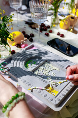 Obraz premium Hobby concept.Top view of artistic female hands creating beaded bracelet.