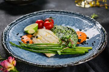 Halibut fillet with spinach, asparagus, and cherry tomatoes on blue ceramic plate, vibrant colors, natural lighting