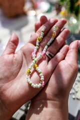 Hobby concept. Hands of a woman holding a handmade necklace. View from above.