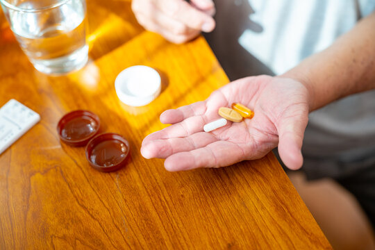 Asian senior man patient taking medicine pill with drinking water from a glass for relief disease in bedroom. Healthy elderly retired people taking vitamins complex supplement for self-care at home.