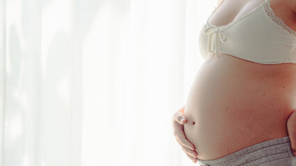 4K Young happy pregnant woman posing in studio with white curtains in background