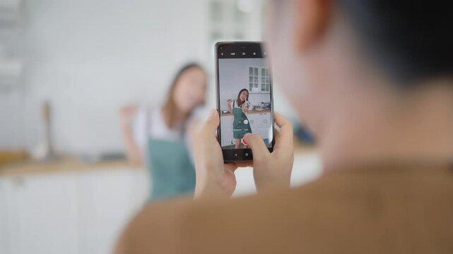 Young asian womans shooting together dancing in kitchen at house when making video for social media, stories trendy dance at home make online content