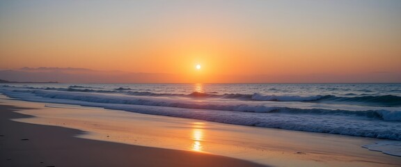 A serene beach scene at sunset with waves gently rolling onto the shore and a vibrant orange sky above