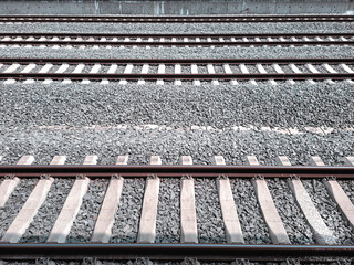 Multiple parallel railway tracks with concrete sleepers and gravel ballast, viewed from above, showcasing transportation infrastructure and linear symmetry.