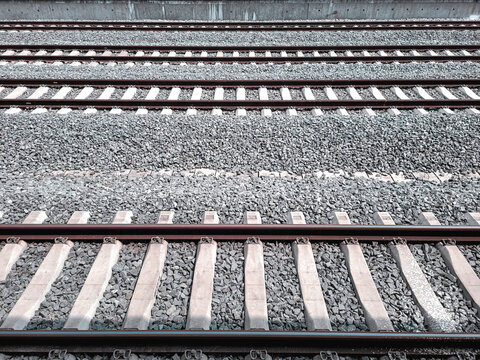 Multiple parallel railway tracks with concrete sleepers and gravel ballast, viewed from above, showcasing transportation infrastructure and linear symmetry.