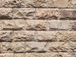 Natural stone wall with rough textured surface and horizontal layout, featuring stacked rectangular blocks in earthy tones for rustic architectural design.